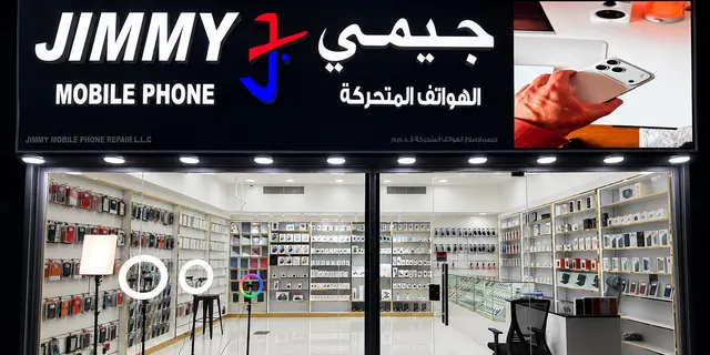 The Jimmy Mobile Phone Repair shopfront lit up at night in Al Barsha 1, Dubai